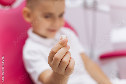 The boy sits in a dental chair on a visit to the dentist and shows a lost tooth