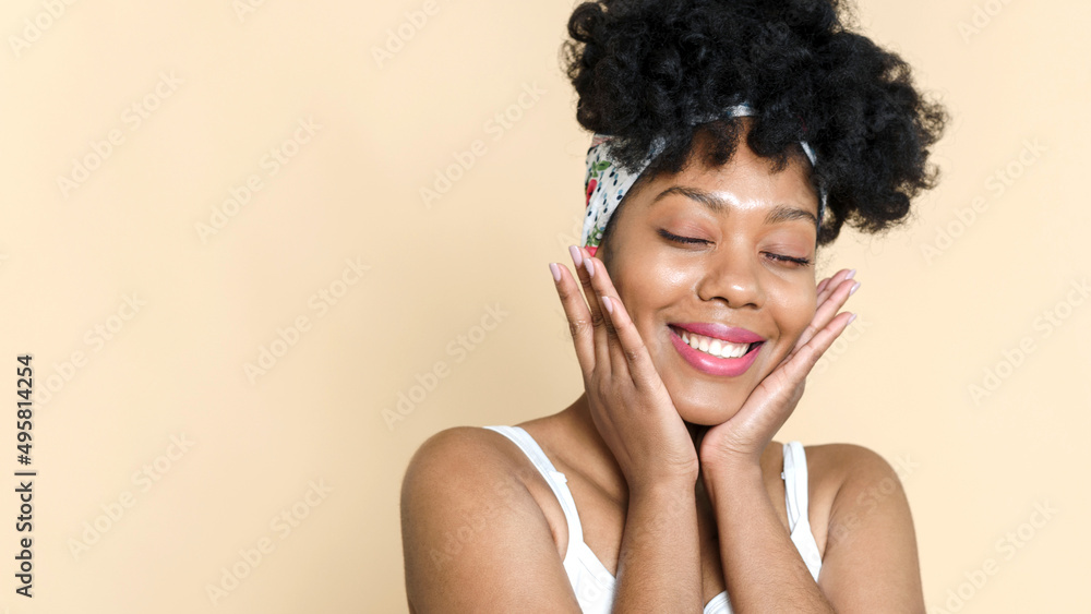 Smiling lovely african american woman touching face skin and smiling on beige background. The concept of natural beauty, beautiful skin. Web banner