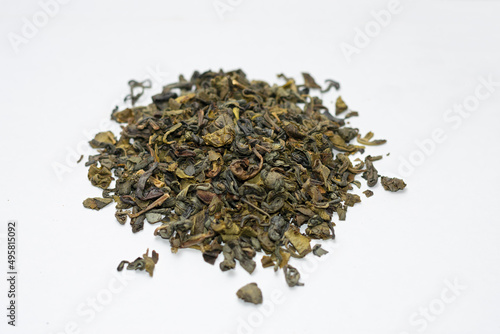 dry green tea leaves piled up on white background