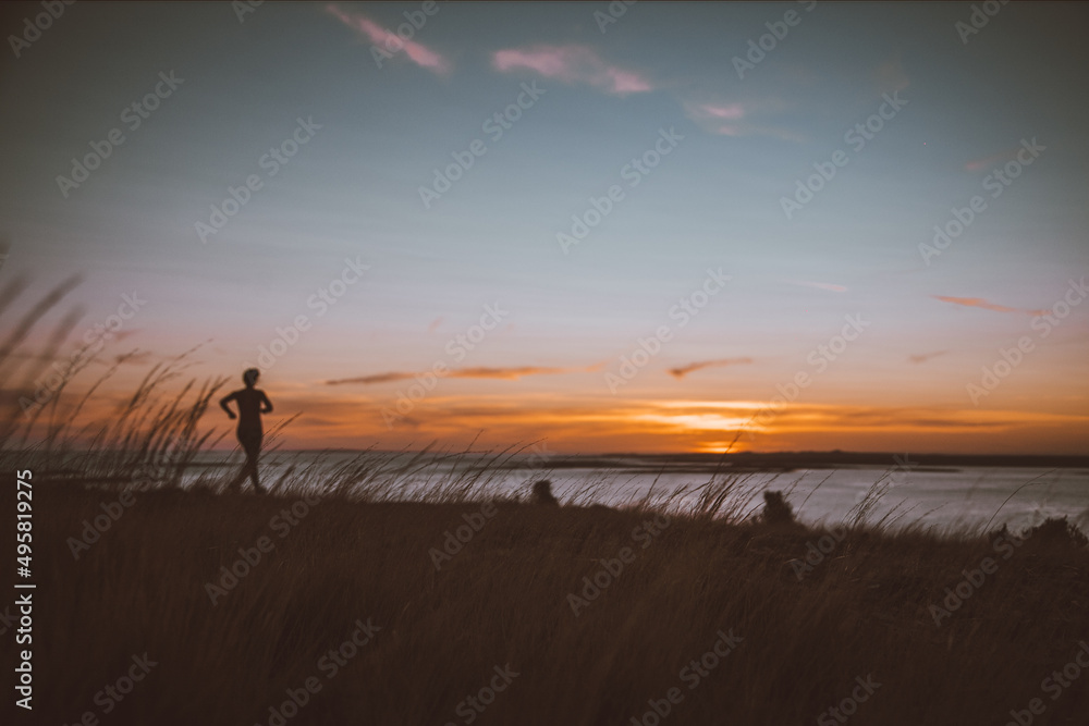 Atardecer y silueta de mujer corriendo