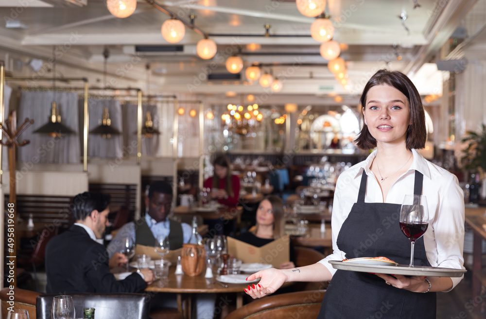 Attractive young waitress with serving tray welcoming in restaurant