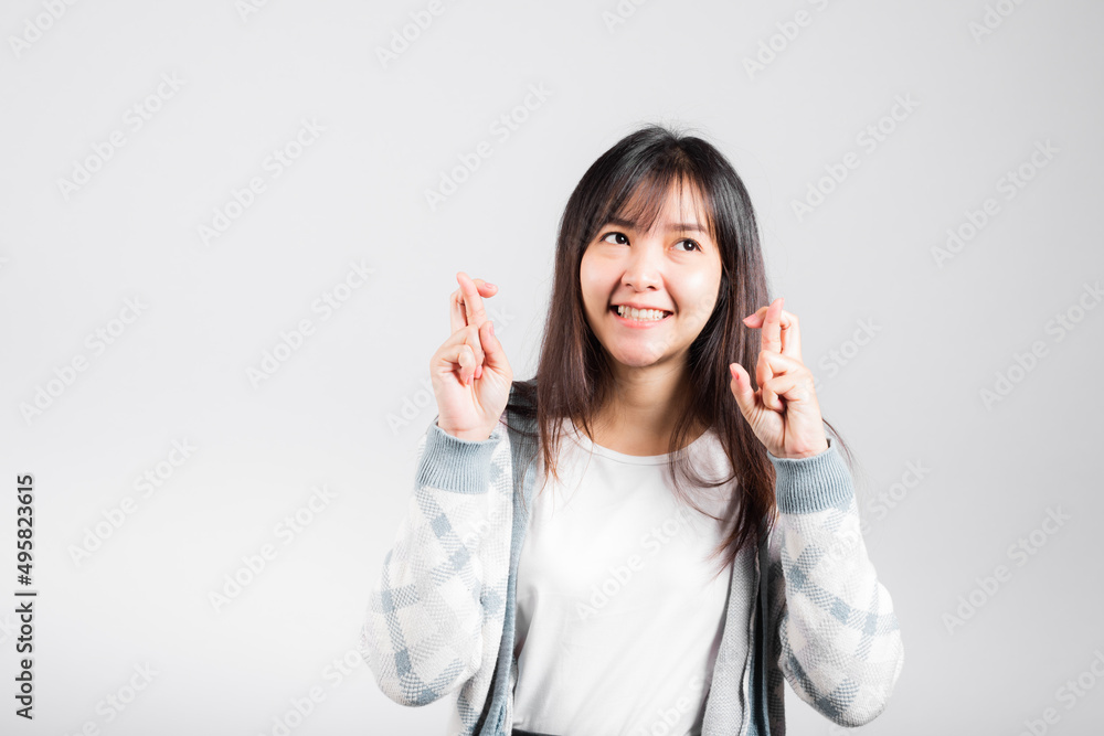 Happy woman have superstition her holding fingers crossed for good luck gesture, Asian beautiful young female smiling superstition, studio shot isolated on white background with copy space Happy woman have superstition her holding fingers crossed for good luck gesture, Asian beautiful young female smiling superstition, studio shot isolated on white background with copy space