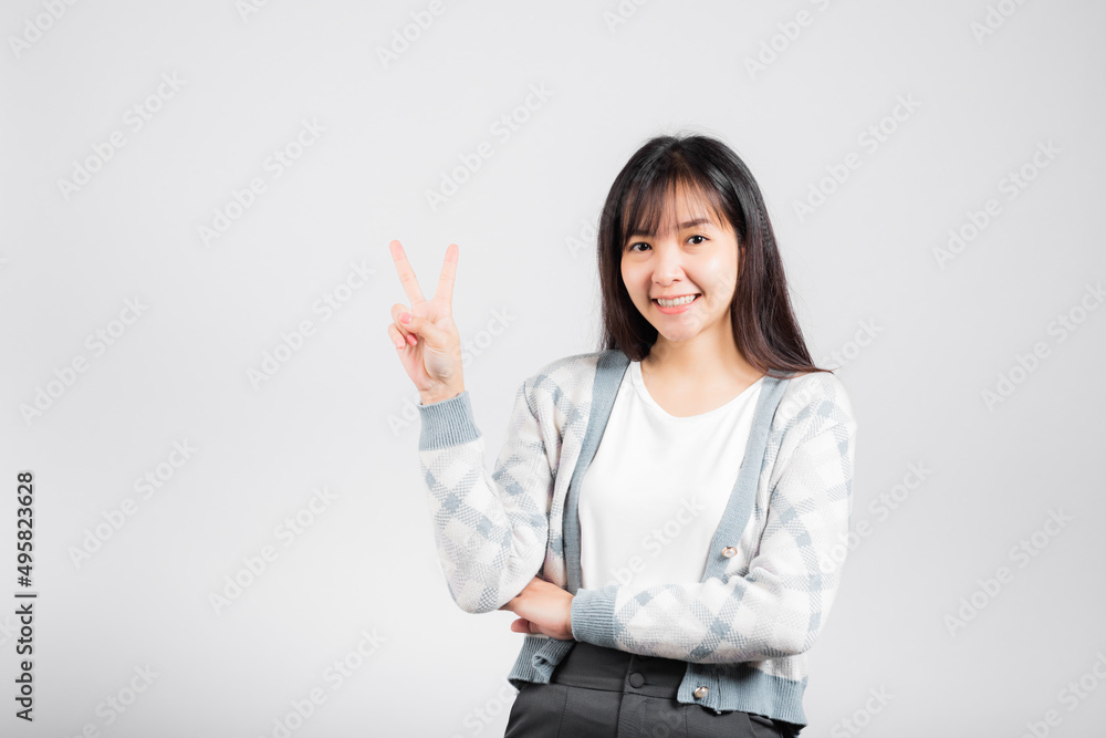 Woman showing finger making v-sign victory symbol side away looking to camera, Happy Asian beautiful young female mark peace gesture symbol, studio shot isolated on white background with copy space Woman showing finger making v-sign victory symbol side away looking to camera, Happy Asian beautiful young female mark peace gesture symbol, studio shot isolated on white background with copy space