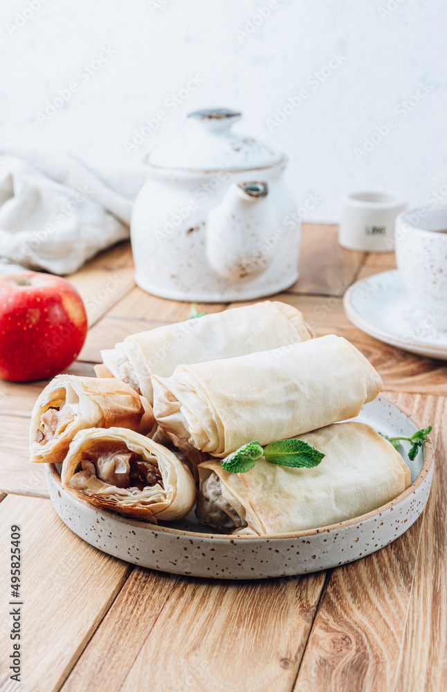 Mini apple strudel with pecans and mint on wooden table. Viennese pastry. Mini apple strudel with pecans and mint on wooden table. Viennese pastry.