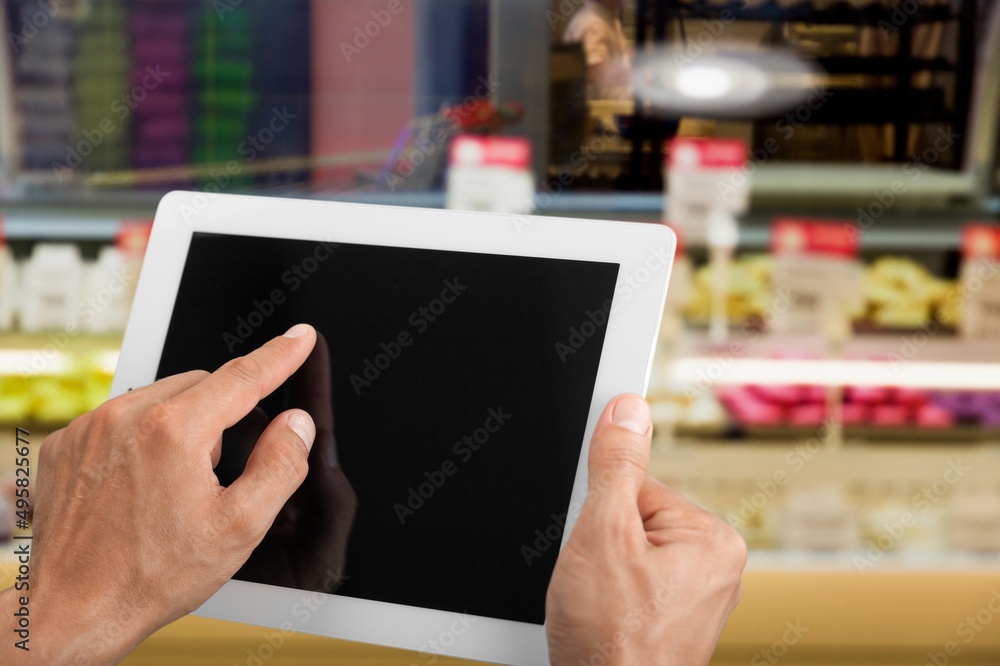 Retail management. Worker hands holding tablet on blurred supermarket