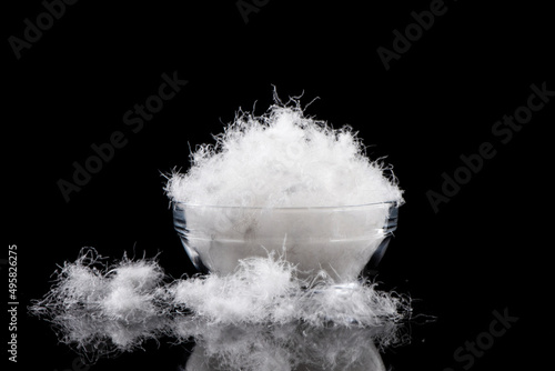 soft fluffy down feather in glass bowl on black background.