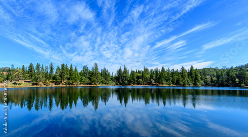 Fototapeta Naklejka Na Ścianę i Meble -  Panoramic scenic view of Lake Tabeaud surrounded by pine and cedar trees under beautiful blue sky