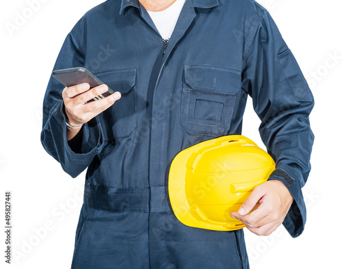 Worker standing in blue coverall holding hardhat and use smartphone photo