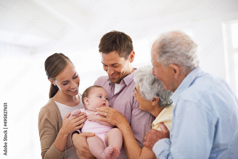 Meeting the newest addition to our family. Portrait of a smiling young couple holding their baby girl while standing with their senior parents. Meeting the newest addition to our family. Portrait of a smiling young couple holding their baby girl while standing with their senior parents.