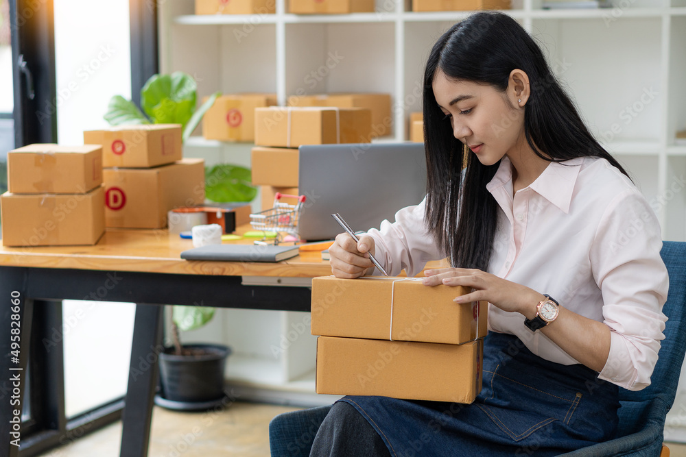 portrait of an Asian woman attractive girl sme business owners starts working with laptop happily with the box at home Prepare to deliver parcels in SMEs, supply chains, online procurement concepts. portrait of an Asian woman attractive girl sme business owners starts working with laptop happily with the box at home Prepare to deliver parcels in SMEs, supply chains, online procurement concepts.