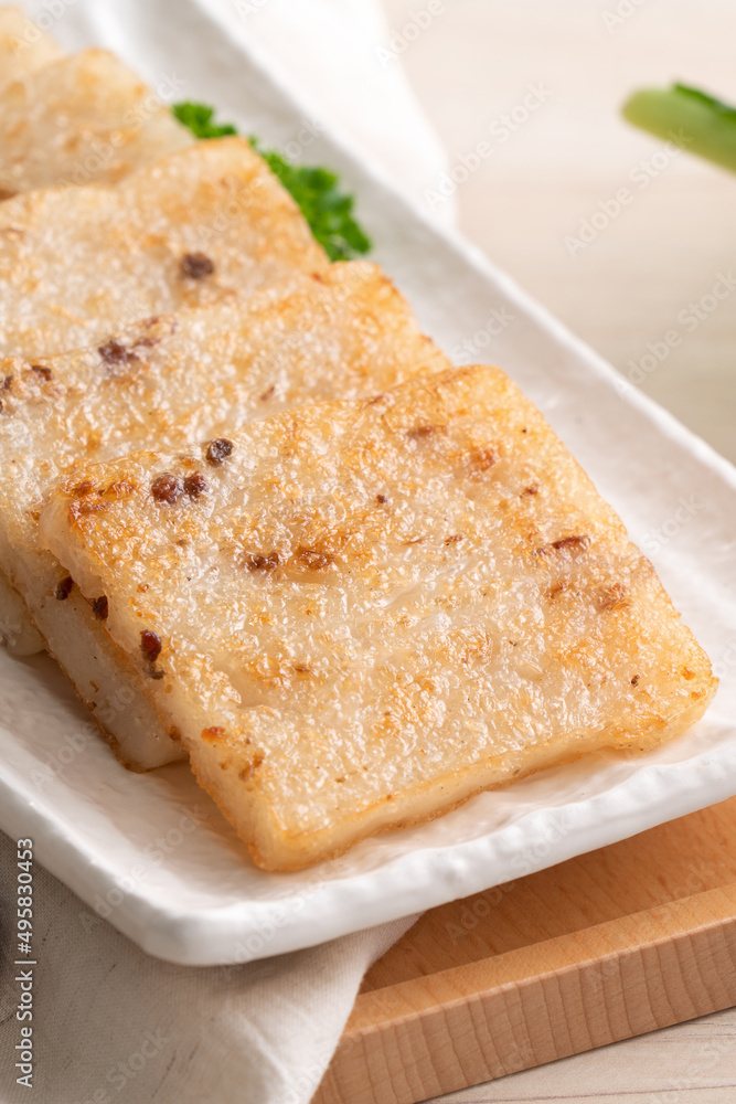 Delicious Chinese radish cake in a plate on wooden table background. Delicious Chinese radish cake in a plate on wooden table background.