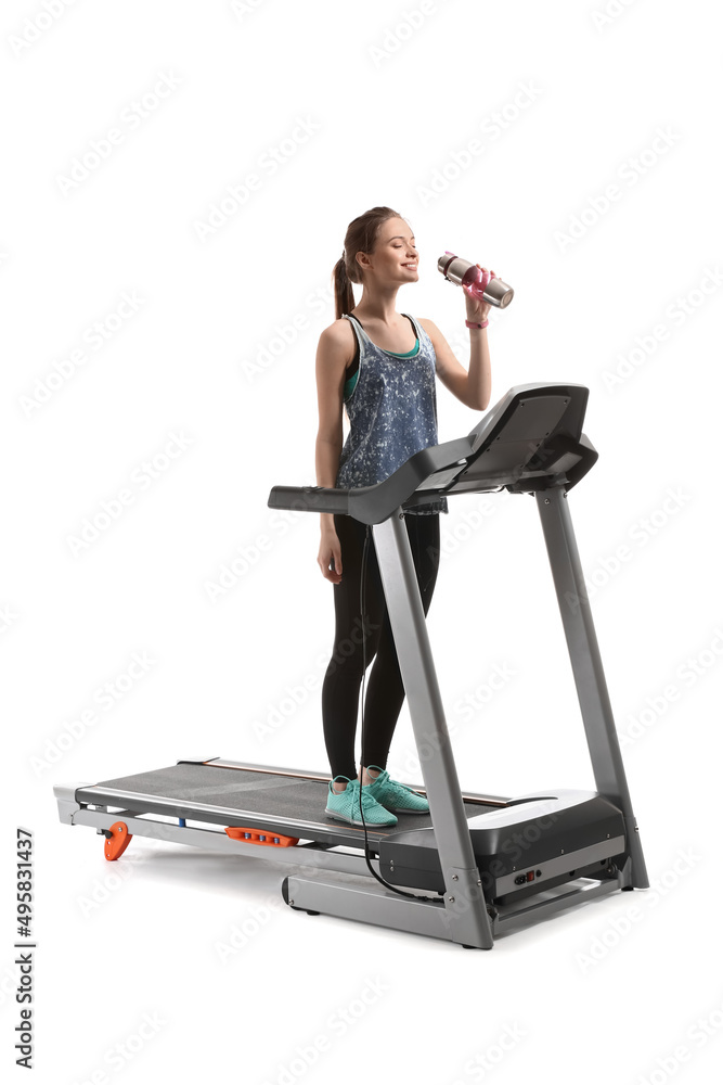 Sporty young woman drinking water after training on treadmill against white background Sporty young woman drinking water after training on treadmill against white background