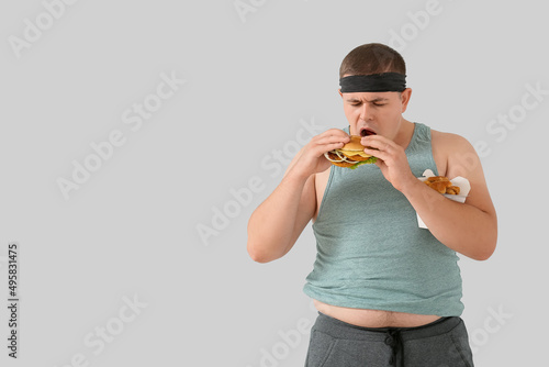 Overweight man eating burge...