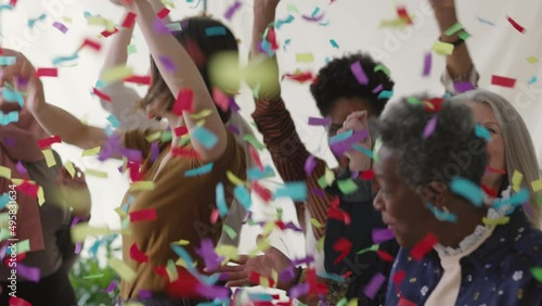 Slow motion of cheerful multi ethnic women celebrating and dancing with ticker tape falling photo