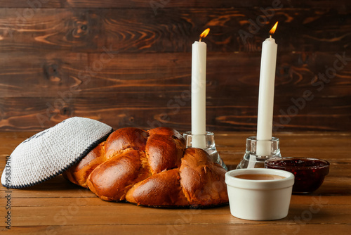 Traditional challah bread with glowing candles and Jewish cap on wooden background. Shabbat Shalom photo