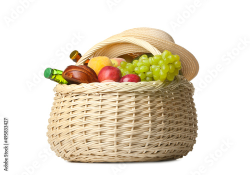 Wicker basket with tasty food for picnic and hat on white background