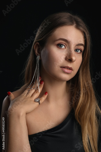 Portrait of young blonde woman with silver jewelry on black background