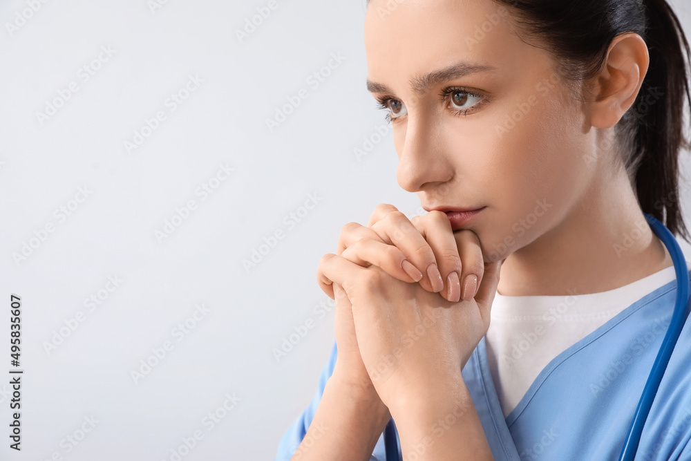 Portrait of praying female doctor on grey background Portrait of praying female doctor on grey background