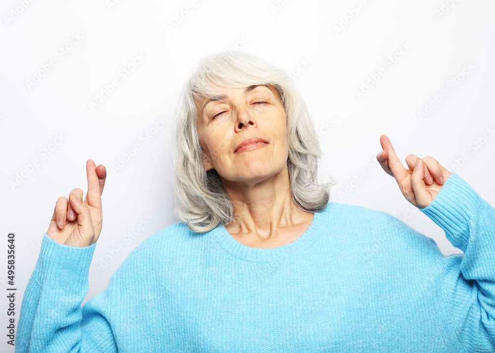 Senior caucasian woman thinking about something pleasant and making wish with crossed fingers isolated Senior caucasian woman thinking about something pleasant and making wish with crossed fingers isolated