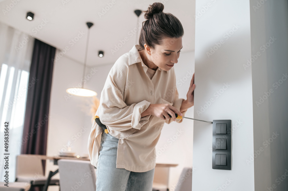 A young woman checking the power socket and looking involved A young woman checking the power socket and looking involved