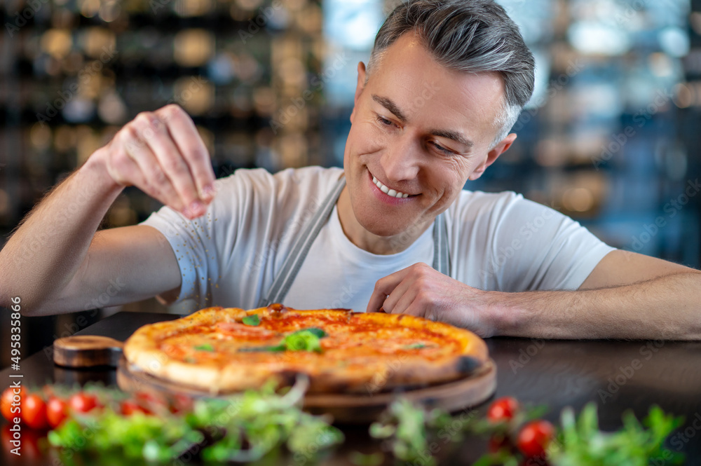 A chef making topping on a italian pizza A chef making topping on a italian pizza