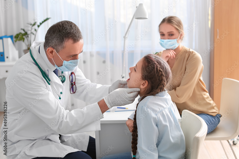 Obraz premium Doctor examining little girl with sore throat in clinic