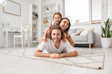 Happy young family lying on carpet at home