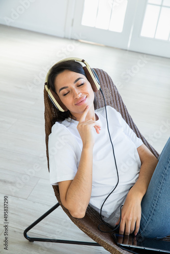 Happy woman with teadphones sitting at chear  at home