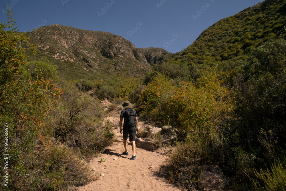 Young man hiking along the dirt path in the mountains.
