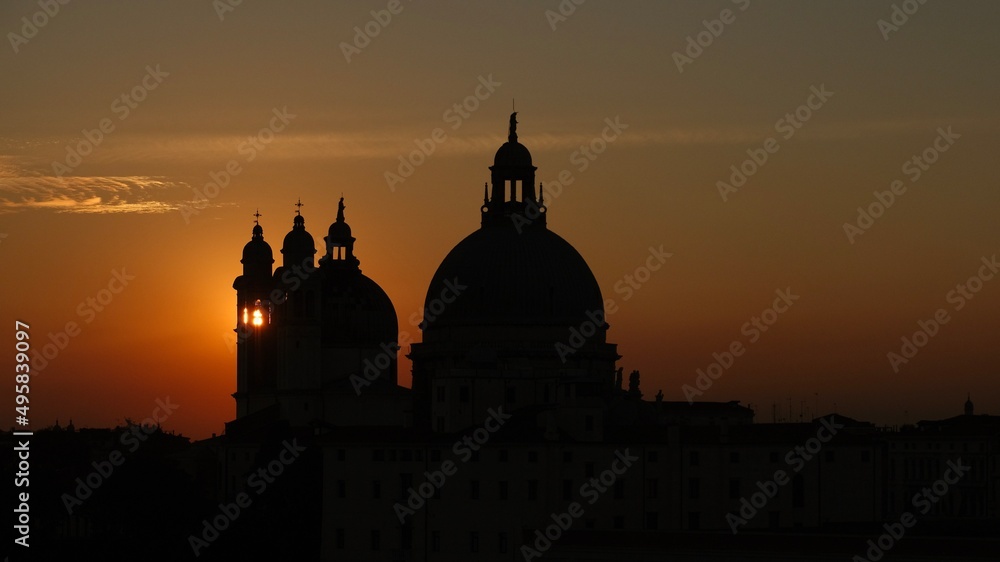 Roof silhouettes against red sky and sunset sun glowing behind. Venice. Italy. 