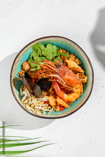 Seafood salad in asian style on white background with hard shadow. Salad with shrimps, mussels, soy bean sprouts. Asian shrimp food. Healthy menu - prawns or shrimp and mussels. Top view seafood.