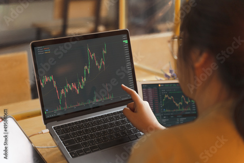 Businesswoman, female trader, investor pointing, using laptop, tablet with graph chart for stock market, Bitcoin cryptocurrency trading, strategy planning on money investing on online trading platform