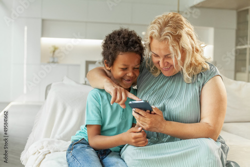 Smiling mother with African American son using gadget at home