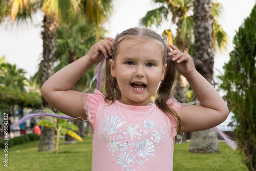Portrait of a cute girl 4 years old dressed in a multi colored dress against the background of palm trees