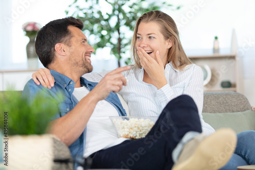 happy couple enjoys watching television and eating popcorn