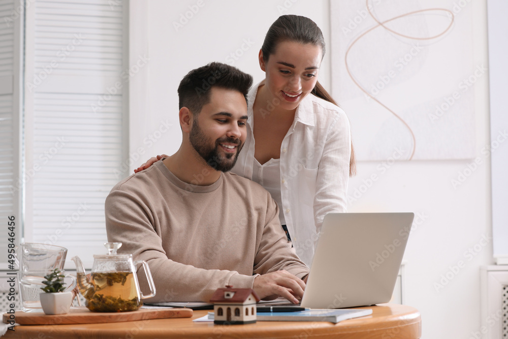 Happy young couple choosing new house using laptop at home. Mortgage concept Happy young couple choosing new house using laptop at home. Mortgage concept
