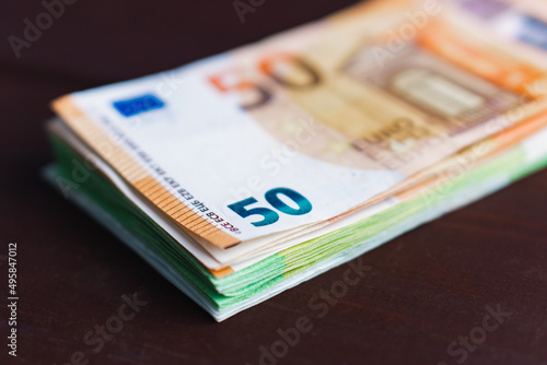 Stack of paper euro banknotes on wooden table. Heap of money. Selective focus. Close-up
