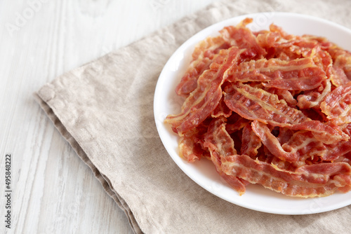 Crispy Fried Bacon on a white plate, side view. Space for text.