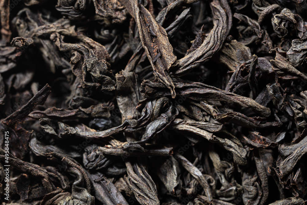 Dried black tea leaves as background.