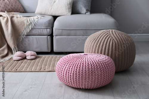 Stylish knitted poufs near sofa in living room. Interior element photo