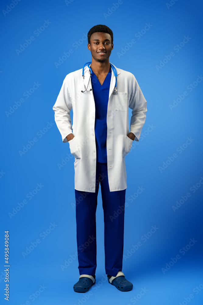 Confident black doctor posing over blue studio background.
