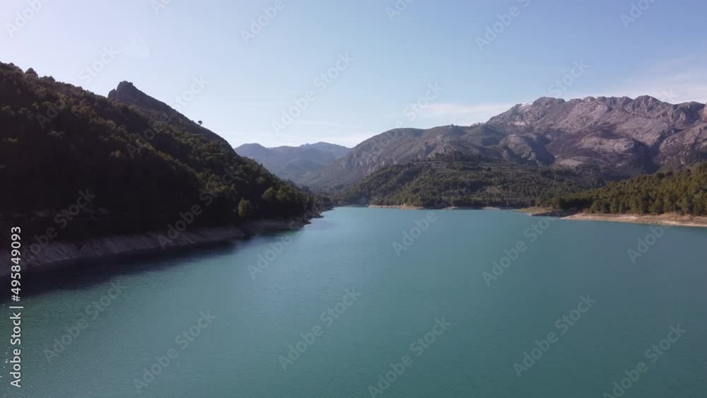 Guadalest water reservoir with coastline surrounded by mountains and forest on a sunny day with blue sky, drone shot - Spain, Alicante Guadalest water reservoir with coastline surrounded by mountains and forest on a sunny day with blue sky, drone shot - Spain, Alicante