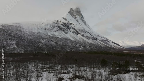 Flying over the forest towards the snow covered Otertinden mountain in northern Norway. 
4k drone shot, push in. photo