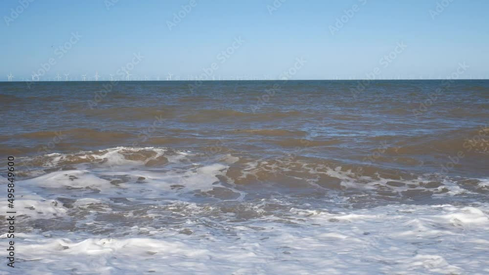 Rolling waves barrel on to pebble beach shore spraying sea foam Rolling waves barrel on to pebble beach shore spraying sea foam