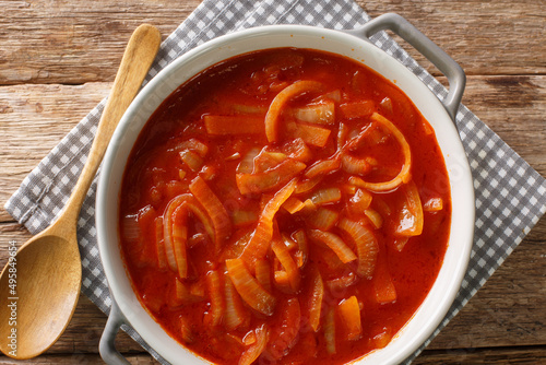 Homemade onion sauce with tomatoes, garlic and spices close-up in a saucepan on the table. horizontal top view from above photo