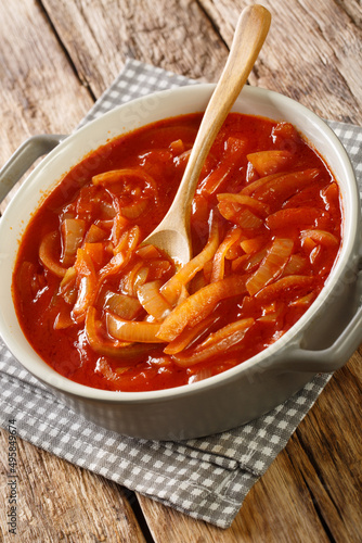 Portuguese Onion Sauce Cebolada close-up in the pot on a wooden table. Vertical photo