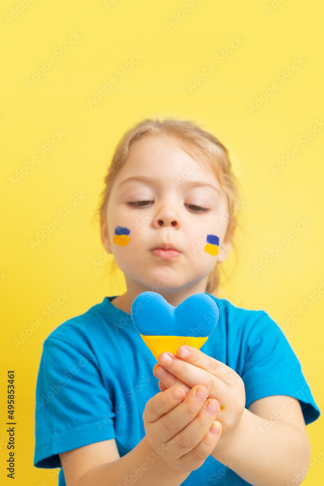 The girl holds a heart of yellow and blue color of the Ukrainian flag