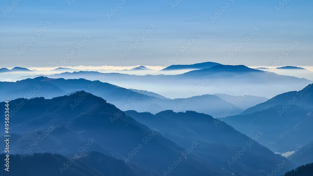A panoramic view on the mountain peaks of the Hochschwab Region in Upper Styria, Austria. Cloudless weather on a sunny summer day in the Alps. Blue misty valley and soft hills. Concept freedom A panoramic view on the mountain peaks of the Hochschwab Region in Upper Styria, Austria. Cloudless weather on a sunny summer day in the Alps. Blue misty valley and soft hills. Concept freedom