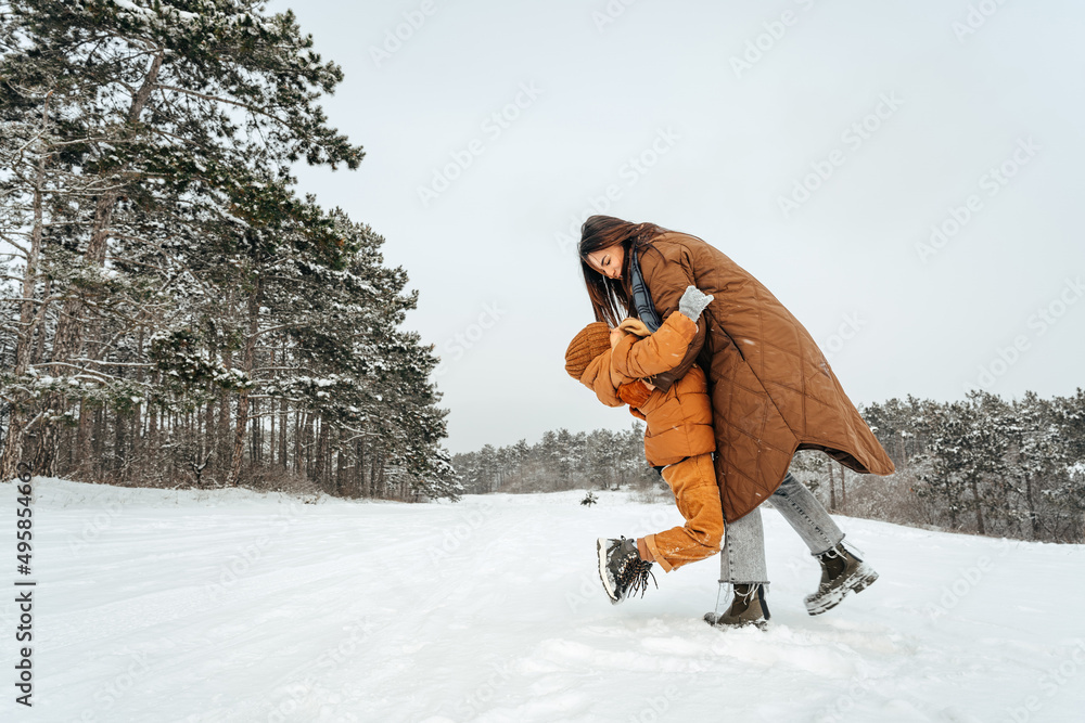 Woman with a little son on a winter hike in the snowy forest