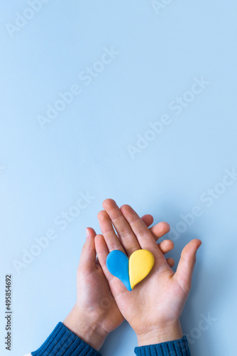 Heart of yellow-blue colors of the national flag of Ukraine in a childs hands, top view